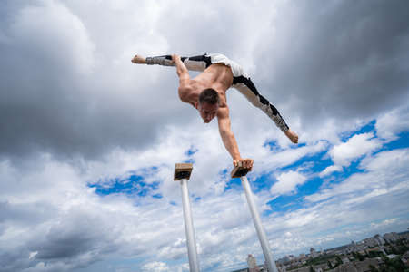 Flexible male circus Artist keep balance by one hand against amazing cloudscape. Individuality, outstanding and originality.の写真素材