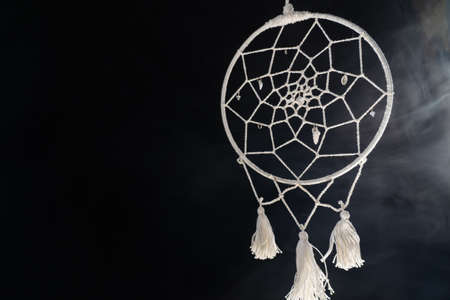Mystical attribute dreamcatcher on a black background with smokeの写真素材