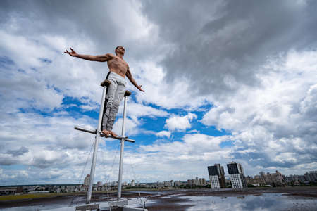 Man standing on the rooftop with dramatic clouds and cityscape on background. Concept of confidence, bravery and individuality.の写真素材