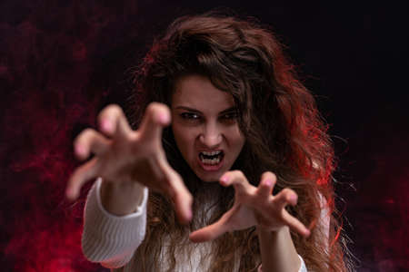 Evil woman on red smoke background. Horror, demon and nightmare conceptの写真素材