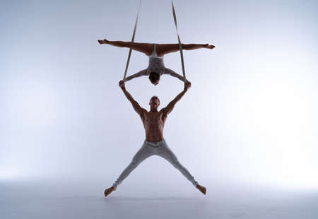 Aerial straps duo wearing white costume on white background doing performanceの写真素材