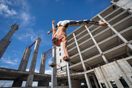 Flexible male circus Artist keep balance on one hand against amazing cloudscape and modern constructions . Individuality, creativity and modern point of view conceptの写真素材
