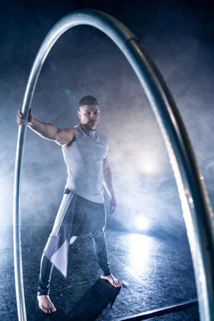 Cyr Wheel circus artist on smoked, dark background performing on stageの写真素材