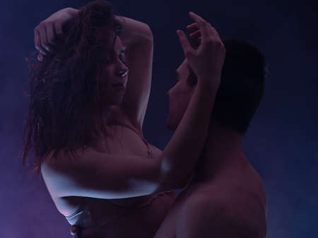 Man and woman hugging with romantic light in darkness. concept of desire, sensuality and romance in coupleの写真素材