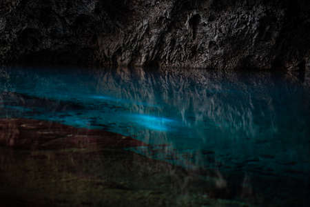 Light descends into the darkness of a submerged cavern with blue lake. Concept of travel and adventure.の写真素材
