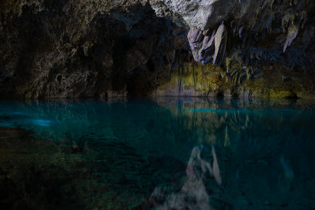 Light descends into the darkness of a submerged cavern with blue lake. Concept of travel and adventure.の写真素材