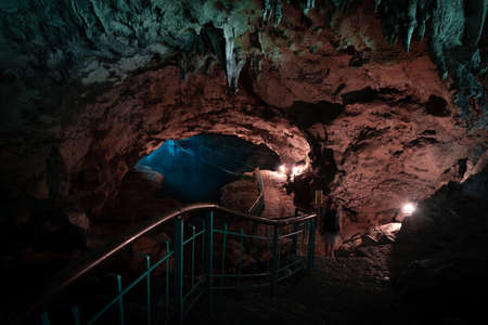 Light descends into the darkness of a submerged cavern with blue lake. Concept of travel and adventure.の写真素材