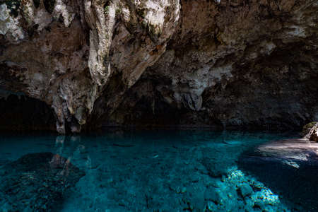 Light descends into the darkness of a submerged cavern with blue lake. Concept of travel and adventure.の写真素材