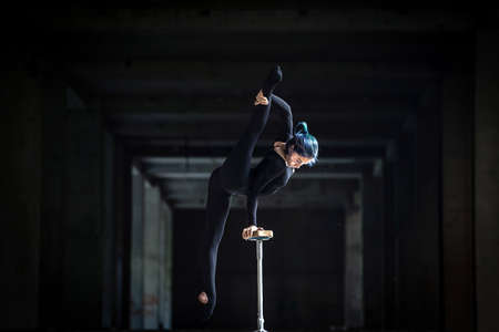 Female flexible circus artist doing handstand in abandoned tunnel. Concept of individuality,...
