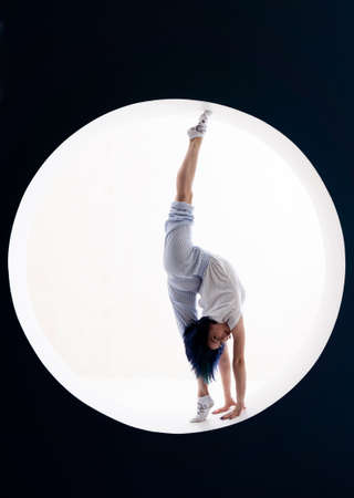 Flexible girl doing stretching and handstand in studio. Concept of individuality, creativity and self-confidenceの写真素材