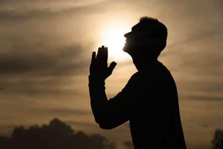 Silhouette of Man pray on during sunset. Repentance, regret and hope conceptの写真素材