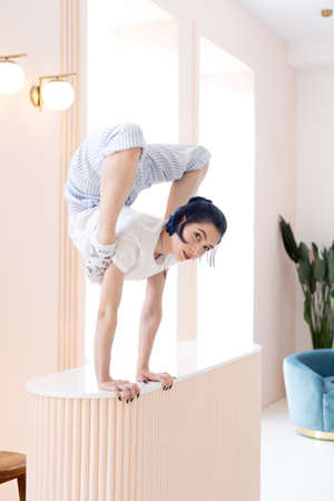 Flexible girl practice stretching and handstand at home. Concept of individuality, creativity and self-confidenceの写真素材