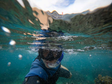 Man in snorkel mask doing selfie underwater. Adventure and travel concept.の写真素材