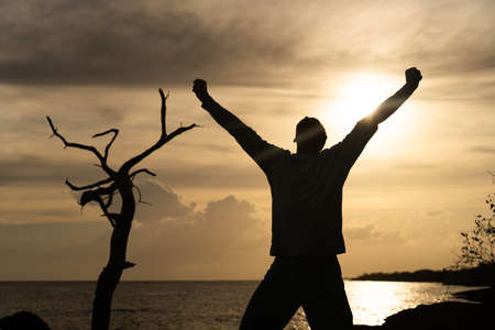 Happy exited Man Jumping on sea and Beautiful Sunrise background. Happiness, joy and success conceptの写真素材