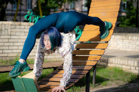 Young flexible woman reading book on the bench bending her back. Yoga, healthy lifestyle conceptの写真素材