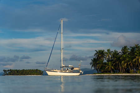 Sailboat in the sea over beautiful islands and palm tree background. Adventure, active vacation conceptの写真素材