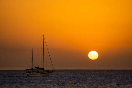 Beautiful sunset with silhouette of sailboat and sun disc. Travel and adventure concept .の写真素材