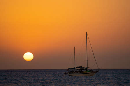 Beautiful sunset with silhouette of sailboat and sun disc. Travel and adventure conceptの写真素材