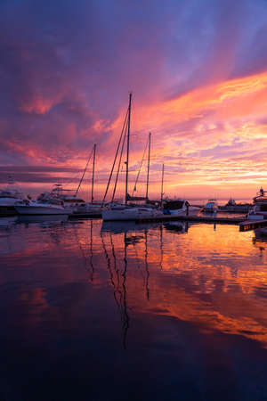 Dramatic sunset over sailboats in the calm water of marina, port, harbor. Travel, vacation conceptの写真素材