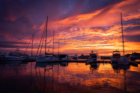 Dramatic sunset over sailboats in the calm water of marina. Travel and adventure concept.の写真素材