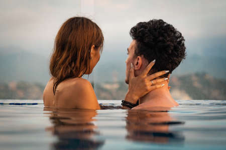 Loving couple in the infinity pole water during sunset. Romantic vacation conceptの写真素材