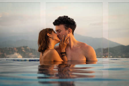 Loving couple kissing in the infinity pole water during sunset. Romance and relationshipの写真素材