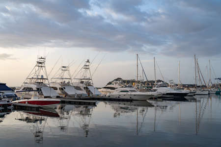 Many motorboats and sailboats Docked at a Marina on dramatic sunrise backgroundの写真素材