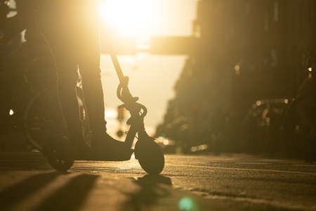 Silhouette of person on electric kick scooter in the city during sunset. Concept of alternative transportationの写真素材