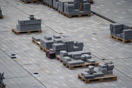 Process of construction of gray brick paved sidewalk, half built pavement roadの写真素材