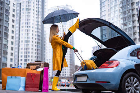 Flexible woman holding split and taking out bags from the car. Flexibility, yoga, stretching and health conceptの写真素材
