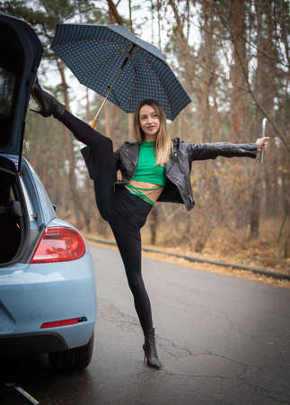 Sexy, flexible woman on the heels hitchhiking on the road. Concept of sexuality and seductionの写真素材