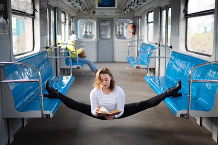 flexible female yogi reading book in the underground carriage sitting in gymnastic split. Concept of inspiration, harmony and health.の写真素材