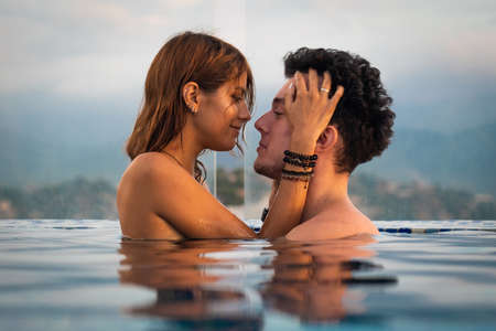 Loving couple in the infinity pole water during sunset. Romantic vacation conceptの写真素材