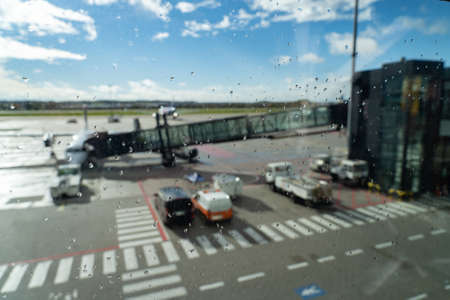 airplane waiting for departure in airport terminal, blurred horizontal background with rain drops. Transportation and logistics conceptの写真素材