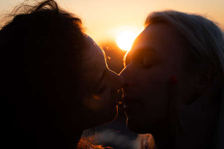 Silhouette of Romantic young couple kissing on sunset. Beginning of lovestory and relationshipの写真素材