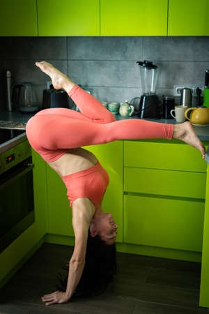 Woman on the kitchen doing exercise and handstand. Concept of individuality, creativity and self-confidenceの写真素材