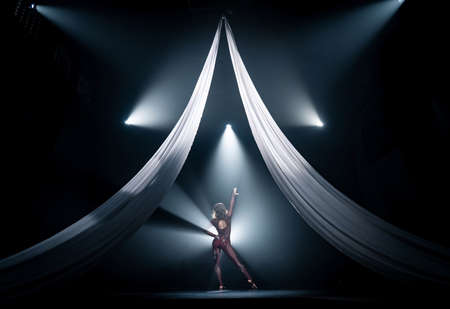 Beautiful circus artist with white aerial silks perform on the stage. Show, art and performance conceptの写真素材