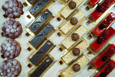 Delicious sweet pastry, cakes and cookies in a row on a showcase in bakeryの写真素材