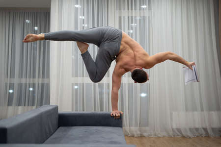 Man keep balance on one hand and reads a book. Handstand, education, studying and knowledge conceptの写真素材