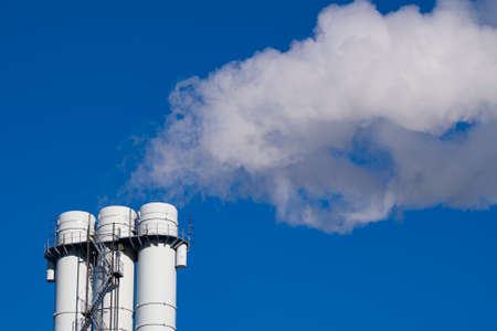 Air pollution by smoke coming out of pipes against blue sky. Concept of pollution, environmental...