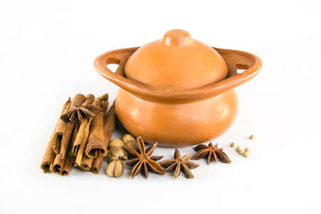 Brown pot decorated with cinnamon and star anise and pepper on white background 