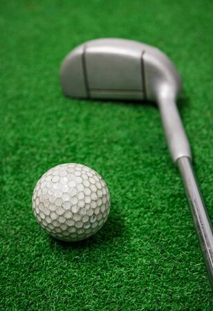 Golf ball and golf clubs on grass.