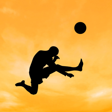 Silhouette boy jumping to kick the ball on the sky and cloud.の写真素材