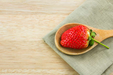 Strawberry on wood spoon with napkin on  wood background.の写真素材