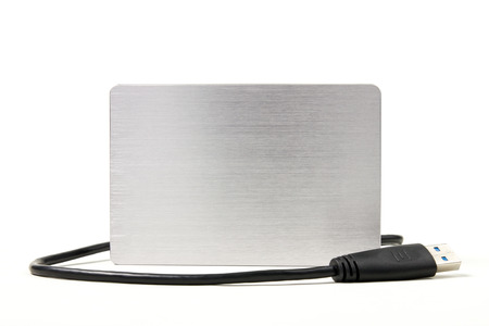 Metallic external hard drive, portable hard disk with USB cable link isolated on white background.の写真素材