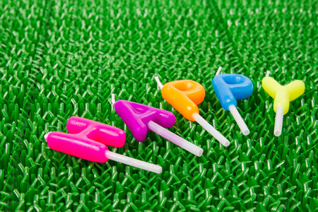 Happy letter made from candle on green plastic grass background.の写真素材