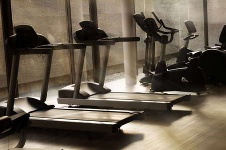 Running machines in fitness center with morning light.