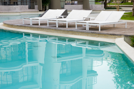 Swimming pool with beach chairs in resort.の写真素材