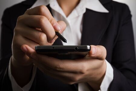 Close up business woman hand holding smart phone and pen.