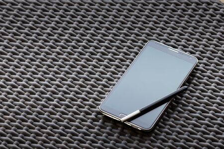 Smart phone and stylus pen on vintage table.の写真素材